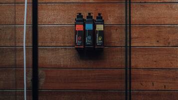 A wooden wall with three black dispensers labeled 'Premium' and a white electrical outlet with a cable.