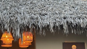 A reception area with a thatched roof, wicker pendant lights, and a sign for Pousada Pacas Suites. - Pacas Suítes (Santo Amaro do Maranhão)