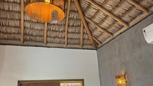 A room with a thatched roof, a wooden door, a window, and a wall-mounted light fixture. - Pacas Suítes (Santo Amaro do Maranhão)