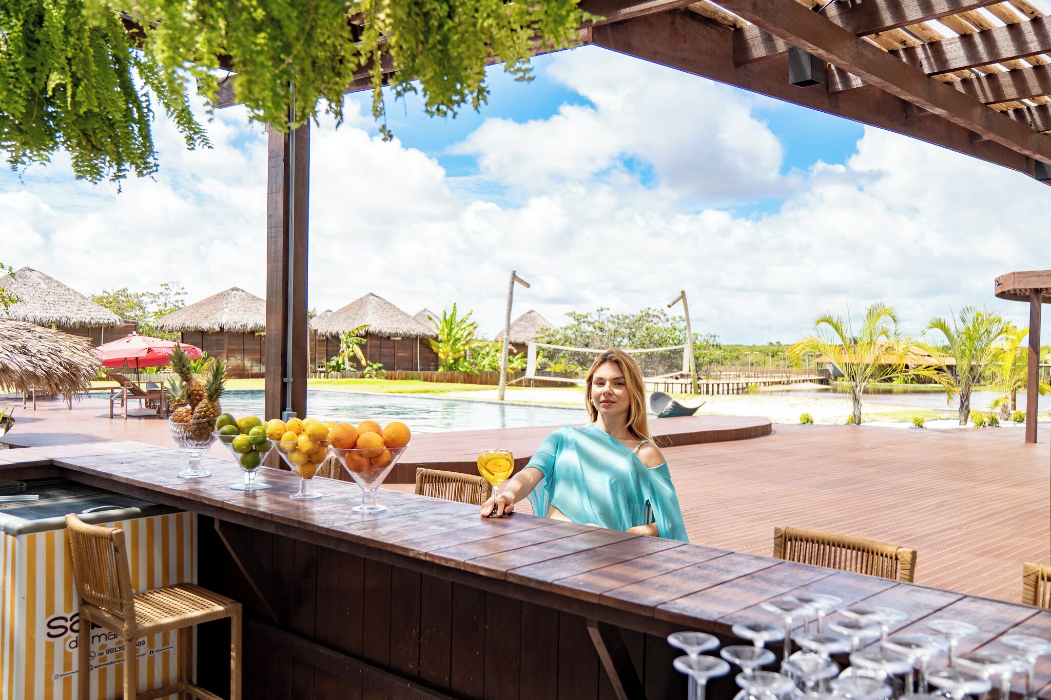 Un espace bar avec vue sur la piscine, une terrasse en bois et une décoration de style tropical.
