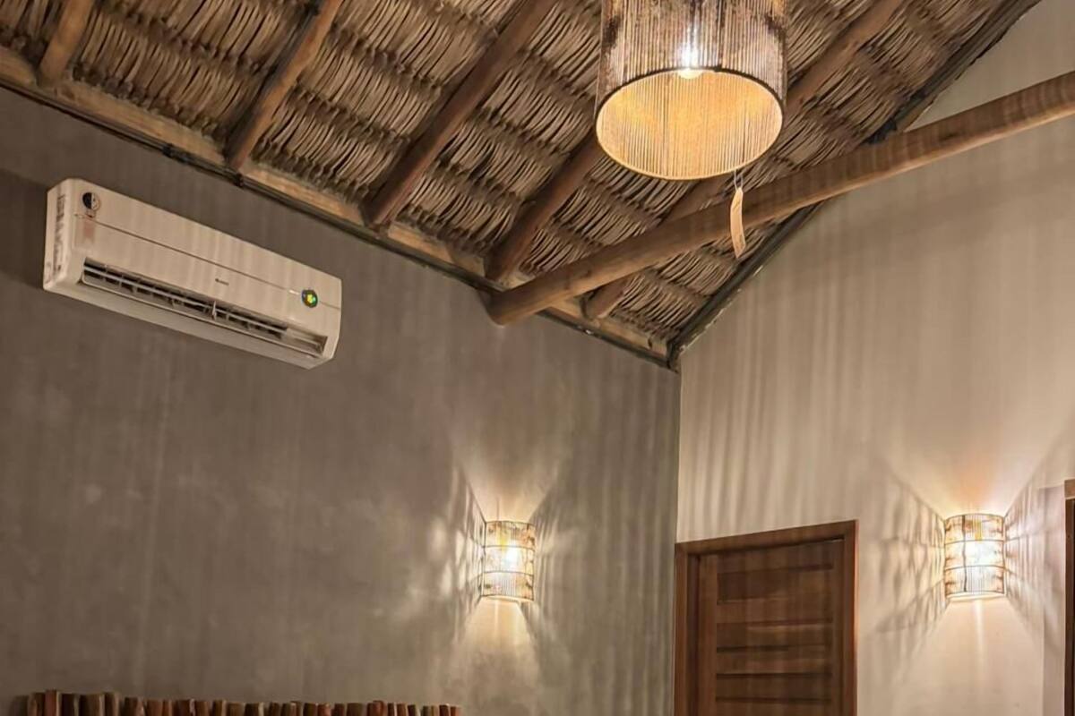 Un dormitorio con una cama, cabecera de madera, equipo de aire acondicionado y dos luces fijadas a la pared.