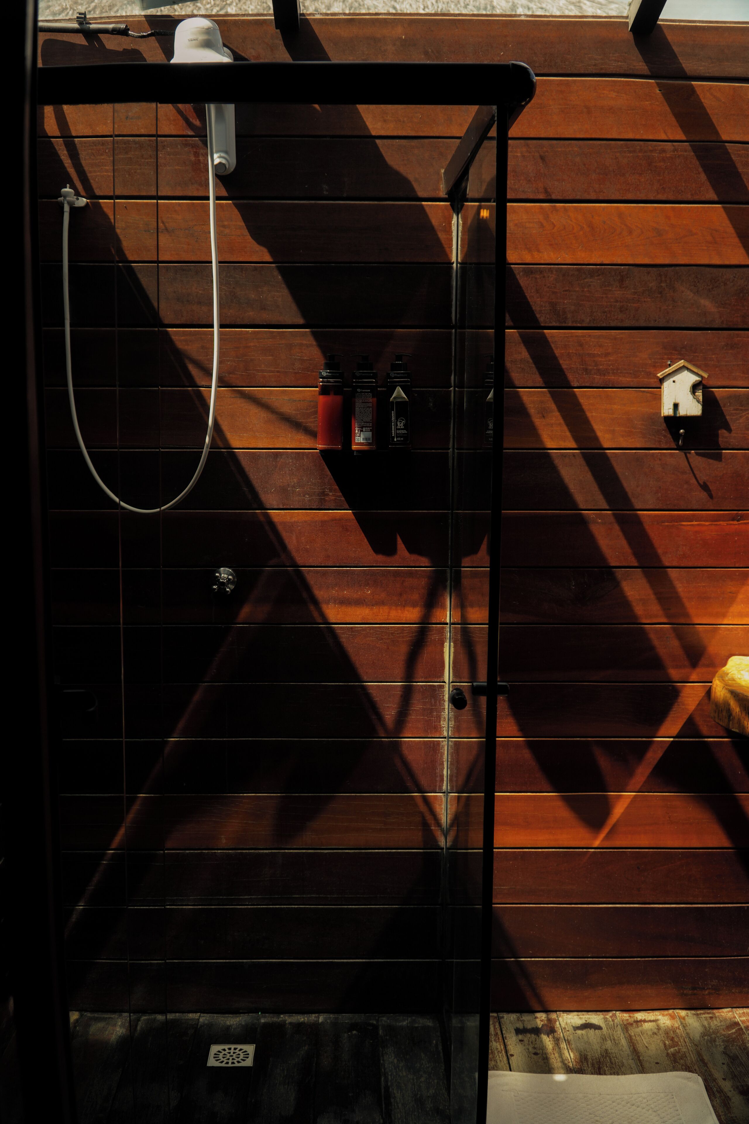 A shower area with a metal door, a handheld showerhead, and a wall-mounted faucet.