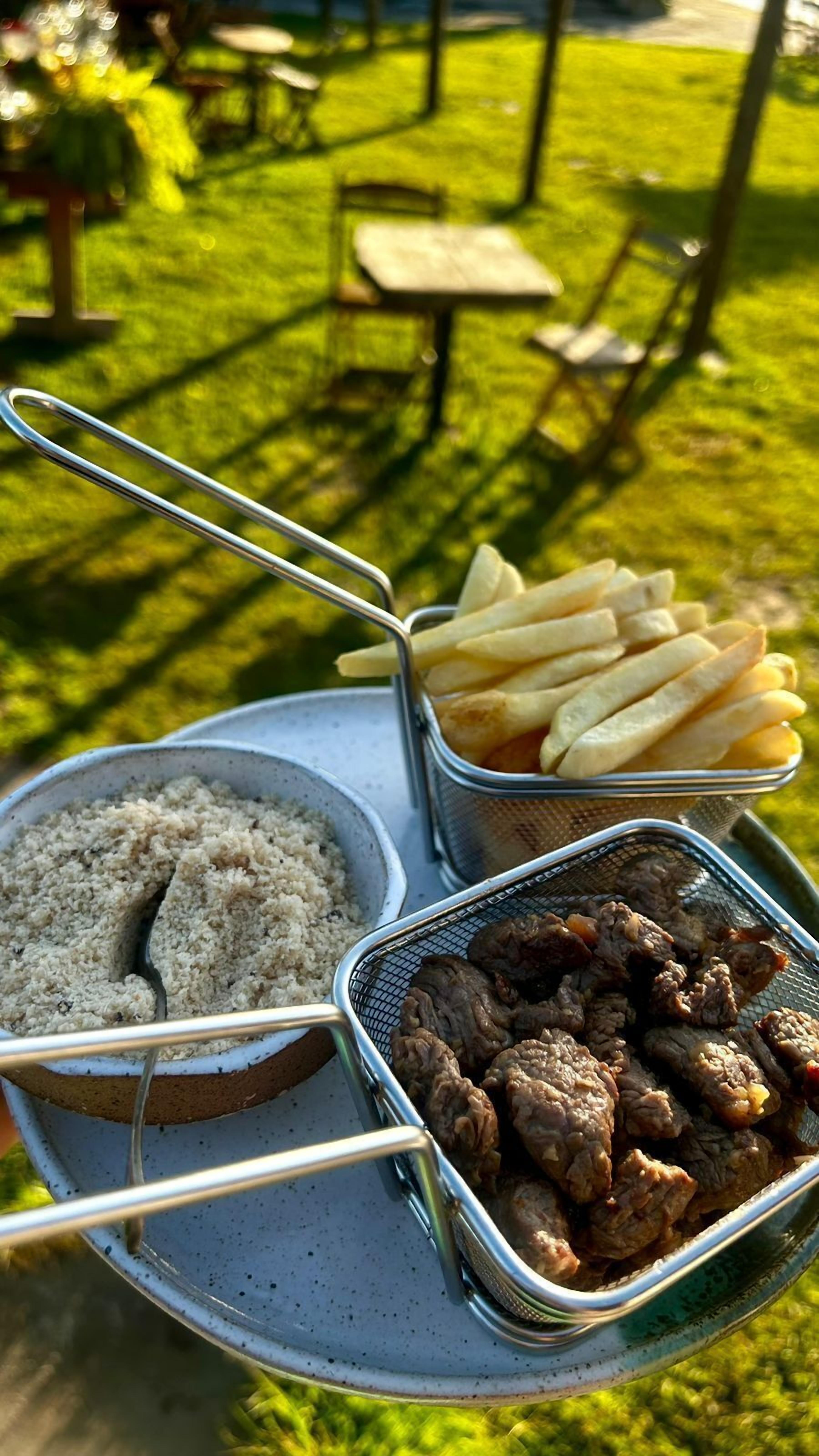 Una bandeja con arroz, papas fritas y carne a la parrilla.