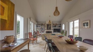 Ett rymligt matområde med ett långt träbord, stolar och en skål med frukt.
