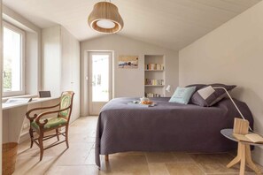 Relax in a serene bedroom with a large bed, a comfortable chair, and a view of the outdoors.