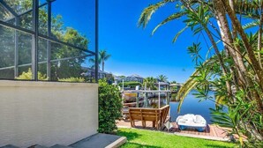 A patio with a view of a lake, a boat, and a bench. - Private Canalfront Pool, Dock & Game Room | Dockside (Palm Coast)