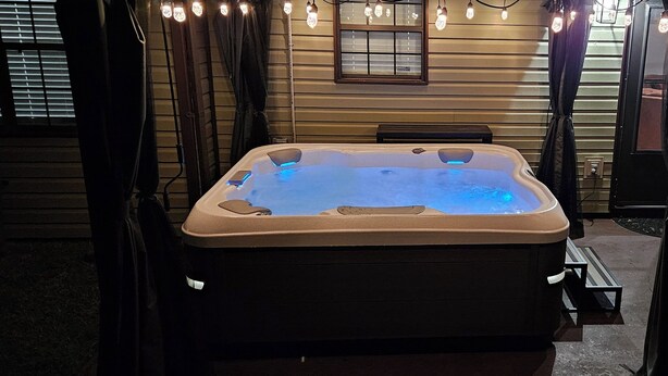 Een hottub in een overdekte buitenruimte met houten wanden en een bank.