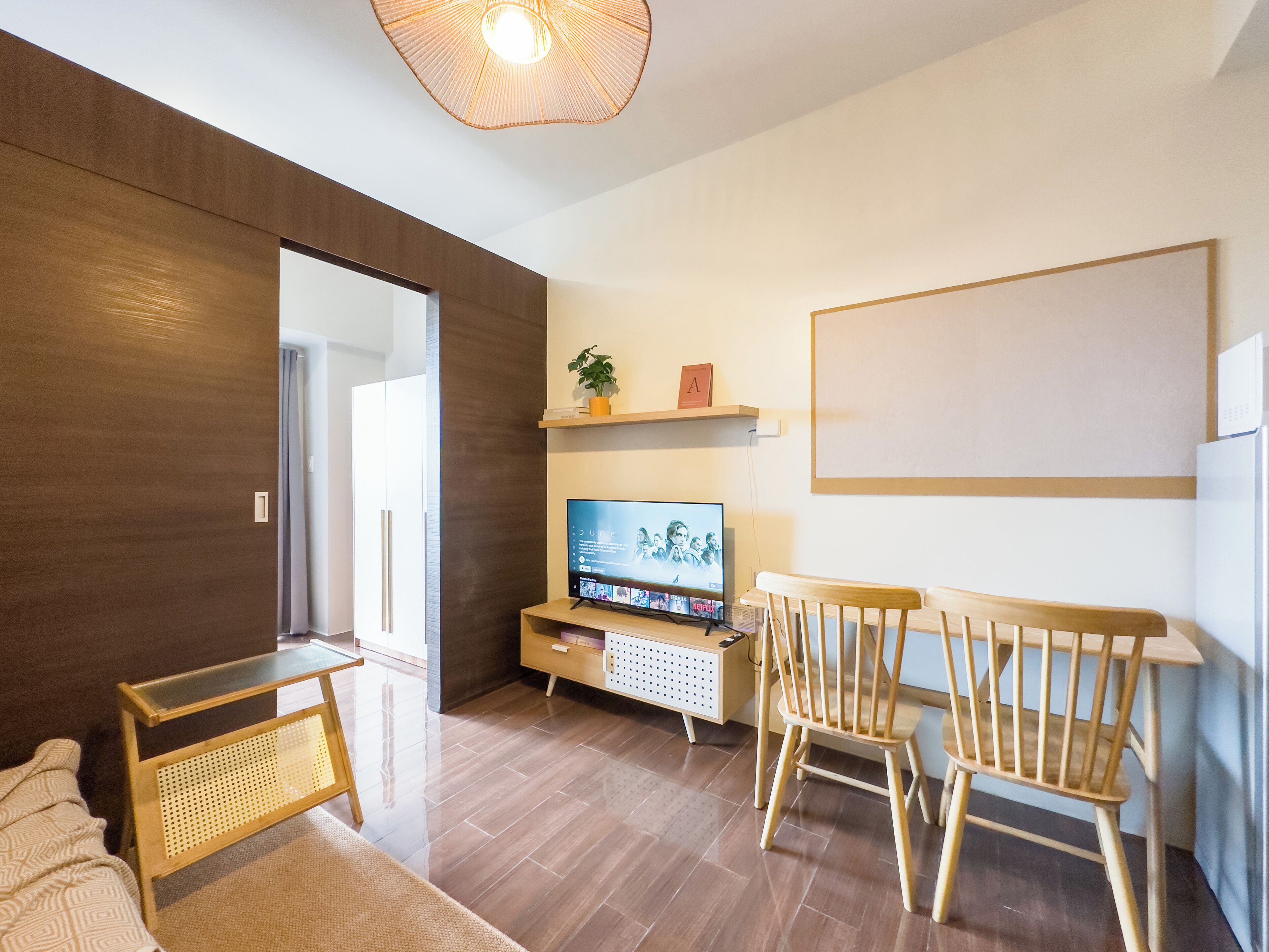 A modern living room with a flat-screen TV, wooden furniture, and a large mirror.