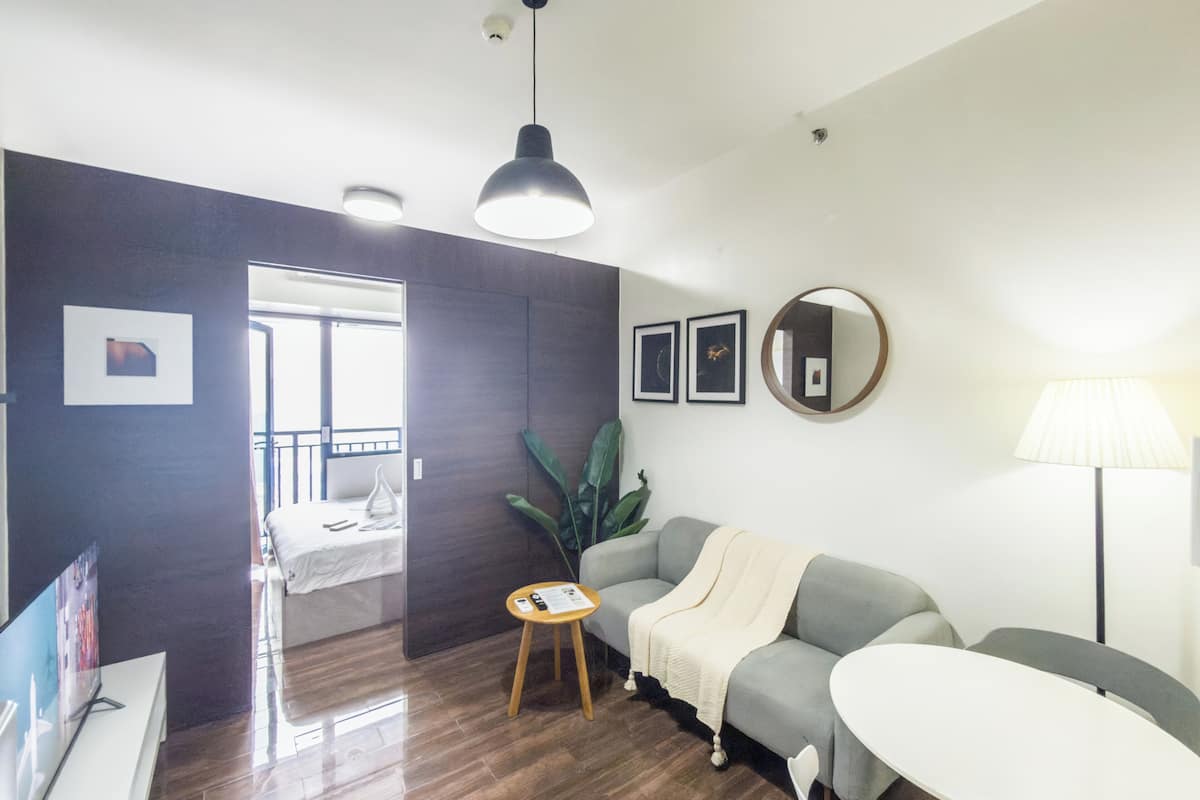 A modern living room with a sofa, a small round table, a lamp, and a large plant.