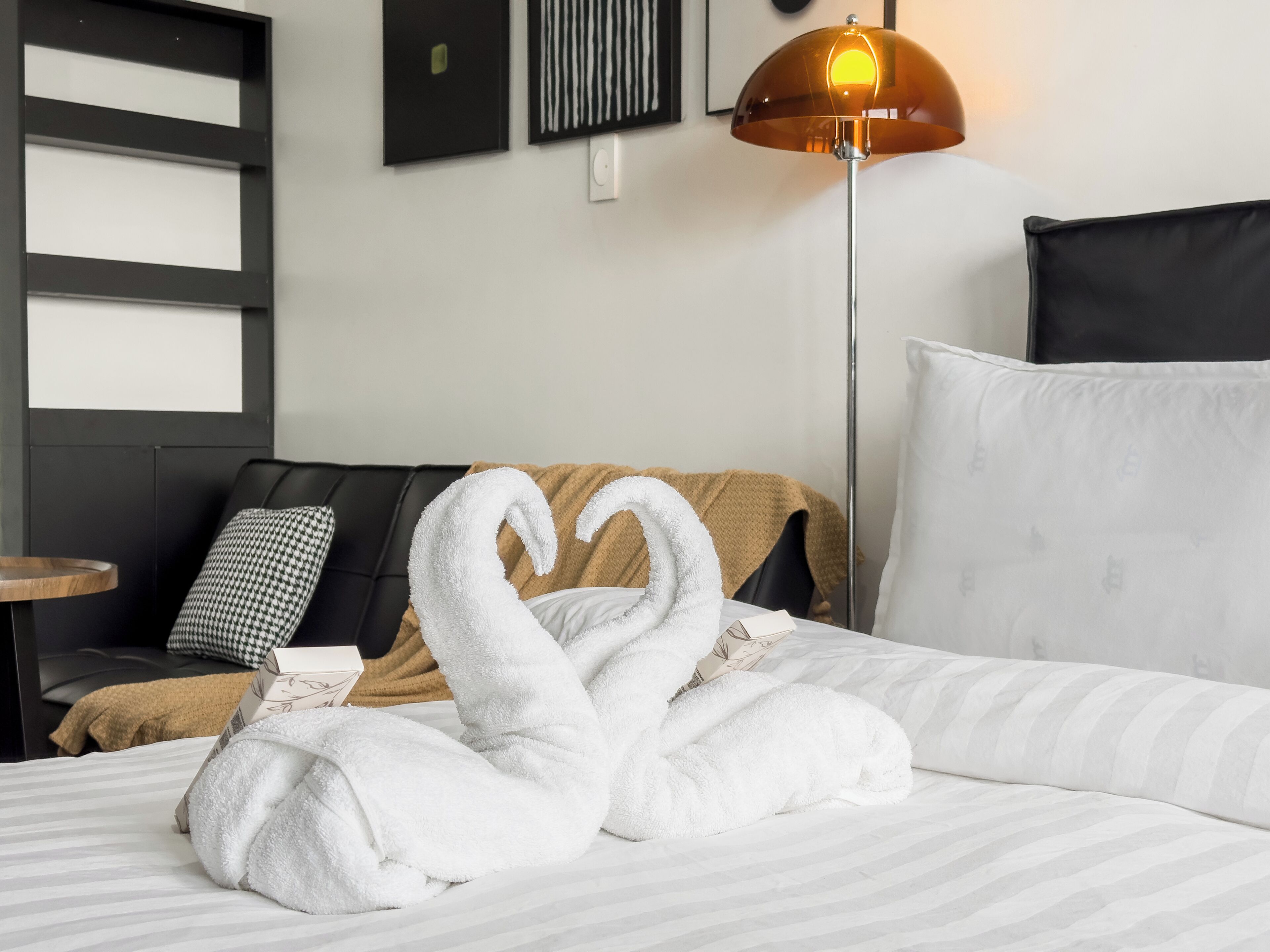 Une chambre d’hôtel avec un lit, un canapé, une lampe sur pied et un mur orné de tableaux.