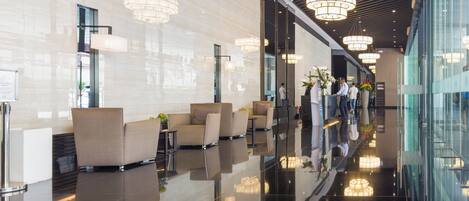 A modern lobby with reflective floors, seating areas, and large pendant lights.