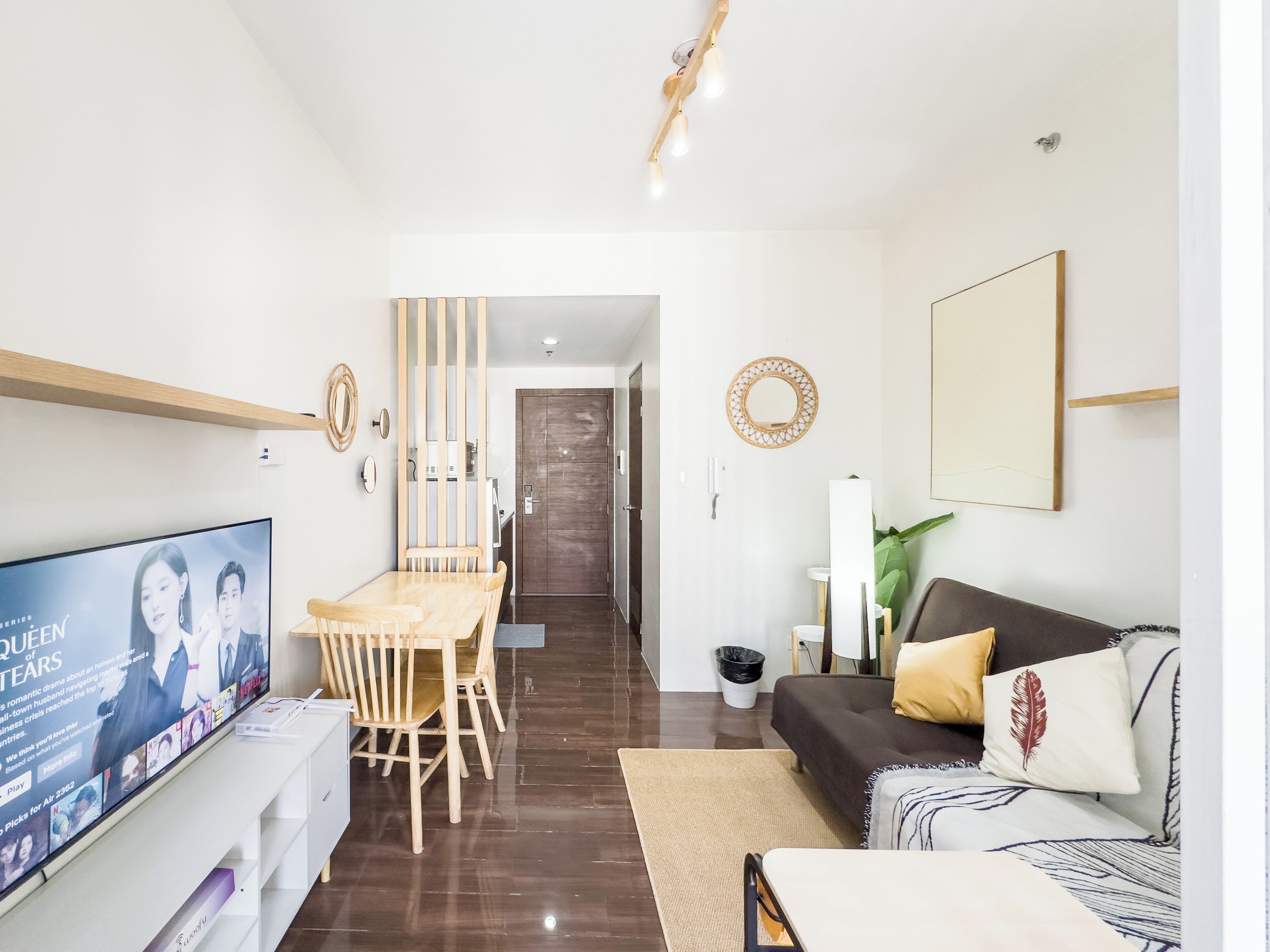 A modern living room with a TV, wooden dining table, and a sofa.