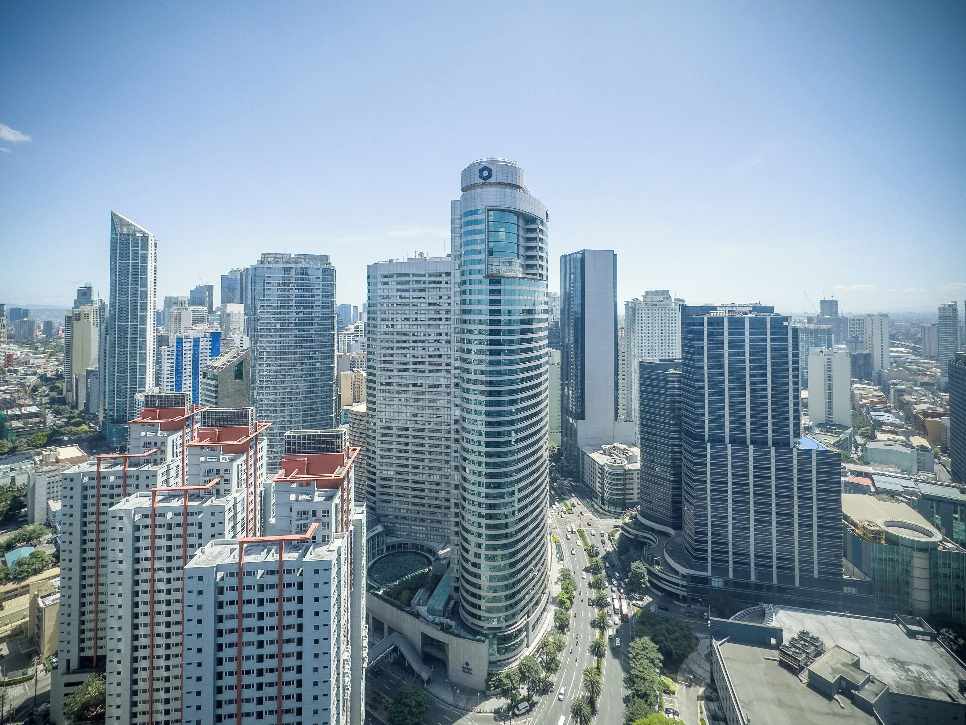 Un quartier urbain caractérisé par de grands immeubles et une architecture moderne, comprenant notamment un bâtiment cylindrique remarquable avec un sommet arrondi et un bâtiment rectangulaire doté d’un toit plat.