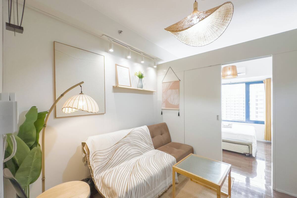 A modern living room with a sofa, a small table, and a hanging light fixture.