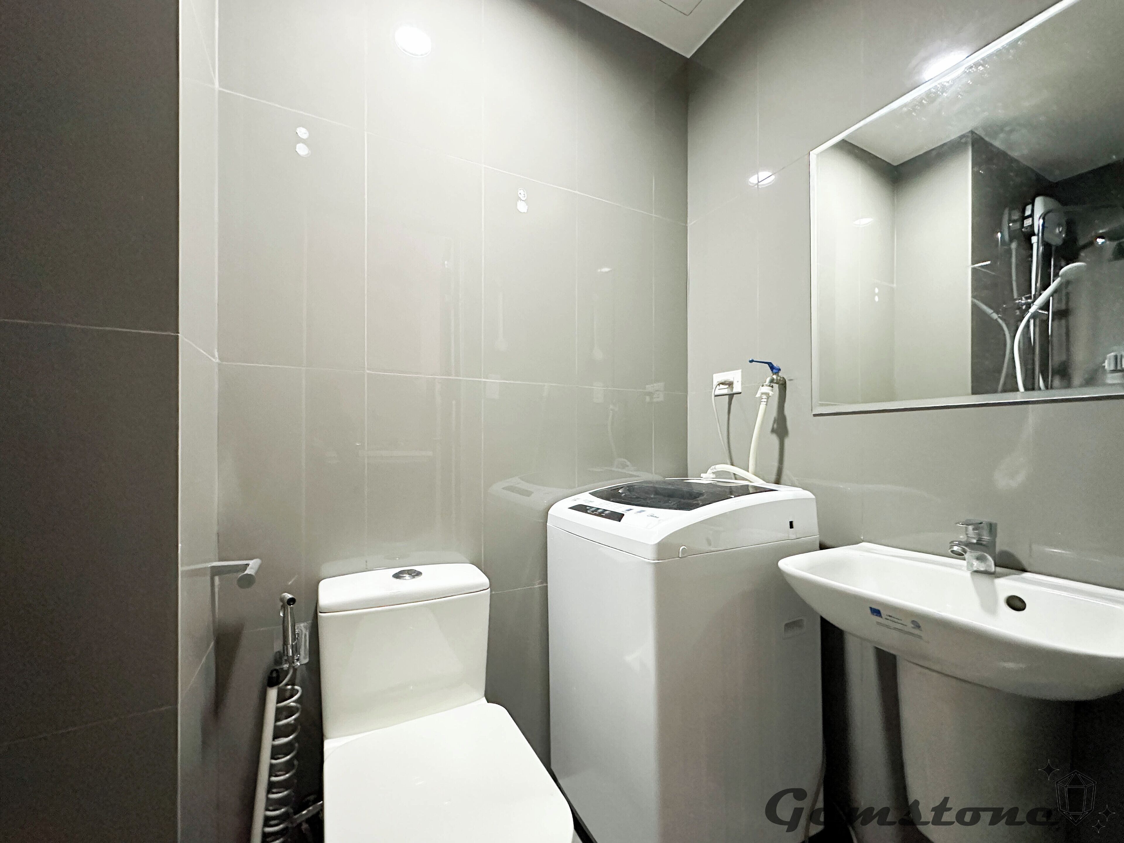 A modern bathroom with a toilet, washing machine, and sink.