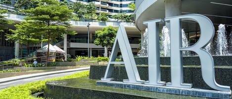 A modern building with a prominent 'AIR' sign, surrounded by greenery and a water feature.