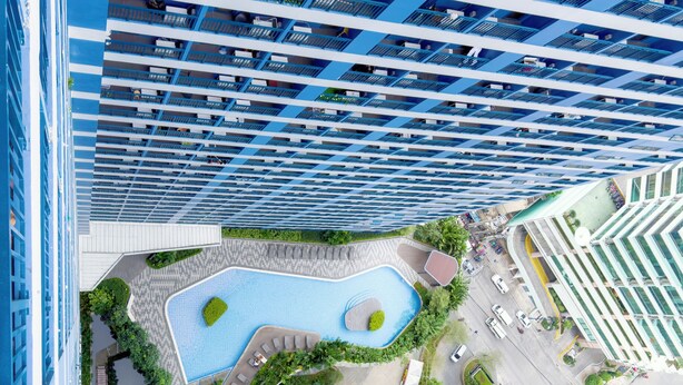 A high-rise building with multiple balconies, a swimming pool, and landscaped areas. - GemstoneBR II in SMDC Air Residences (Makati)