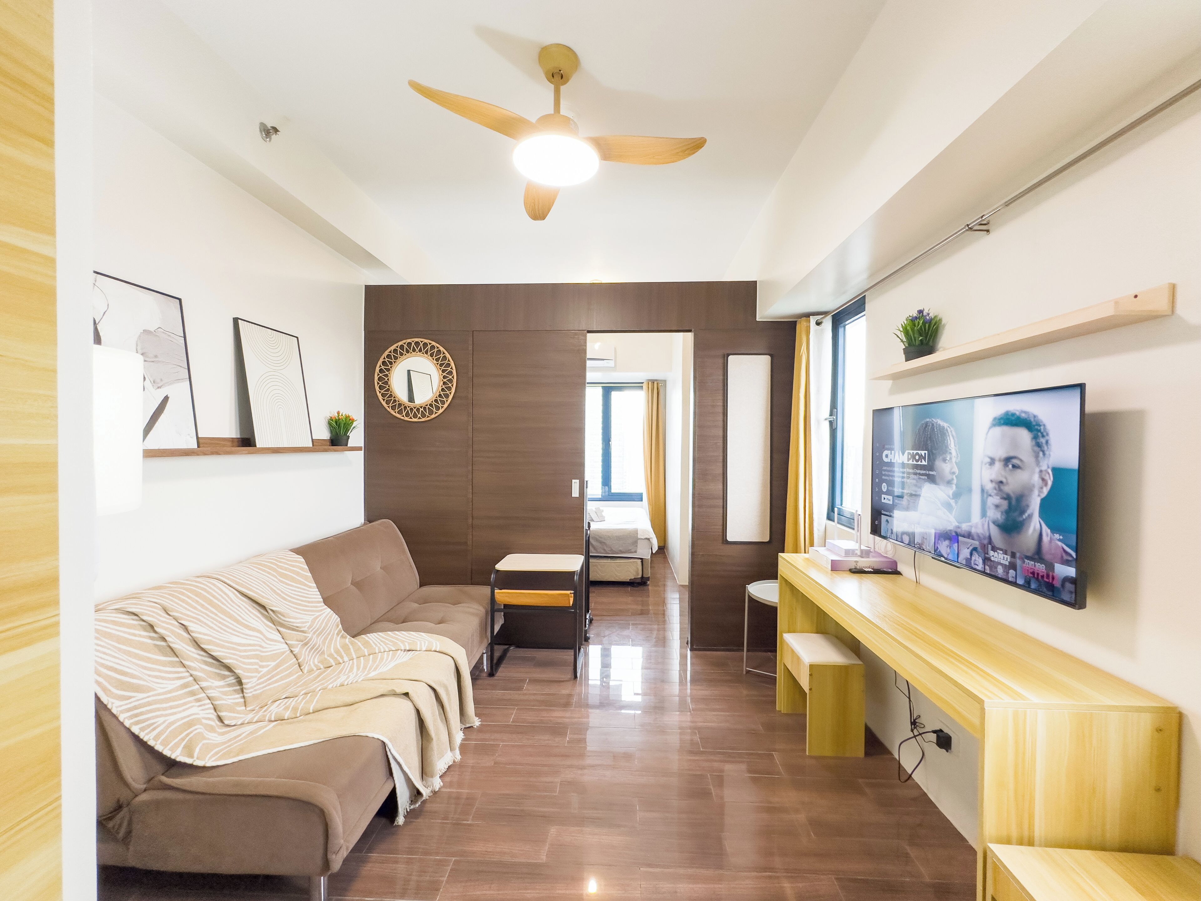 A modern living room with a sofa, a TV, and a ceiling fan.