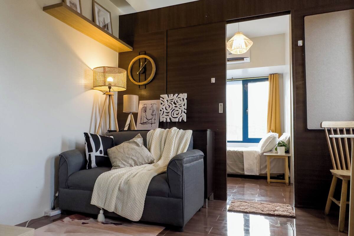 A modern living room with a grey sofa, a floor lamp, and a wall clock.
