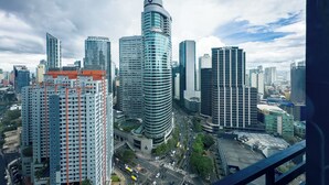 A cityscape with modern high-rise buildings, a curved skyscraper, and a busy intersection. - GemstoneBR II in SMDC Air Residences (Makati)