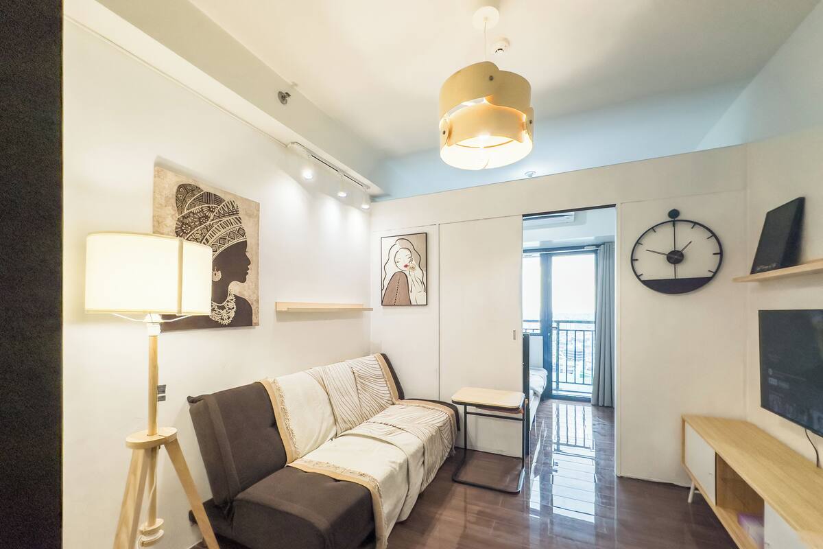 A modern living room with a sofa, a standing lamp, and artwork on the walls.
