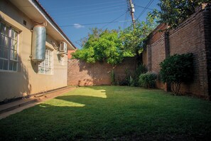 Un cortile residenziale con un muro in mattoni, un serbatoio metallico e un prato.