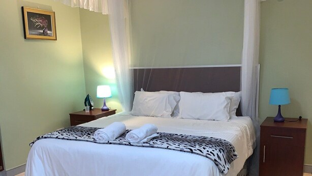 A neatly made bed with a patterned bedspread, two bedside lamps, and a decorative picture on the wall.
