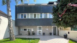 A modern two-story building with a flat roof, large windows, and a paved courtyard. - Koalawakeup (Vitry-sur-Seine)