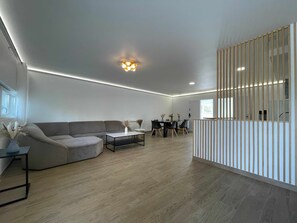 A modern living room with a sofa, coffee table, and dining area with chairs and a table. - Koalawakeup (Vitry-sur-Seine)