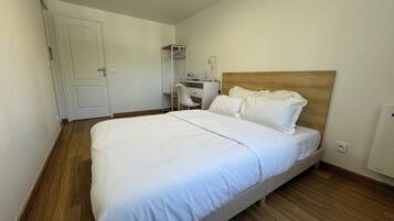 A bedroom with a single bed, a desk, and a chair.