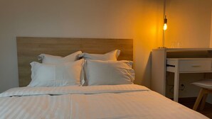 A neatly made bed with white linens, a wooden headboard, and a bedside table with a lamp. - Koalawakeup (Vitry-sur-Seine)