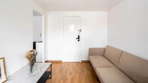 A minimalist living room with a beige sofa, a marble coffee table, and a white door. - Koalawakeup (Vitry-sur-Seine)