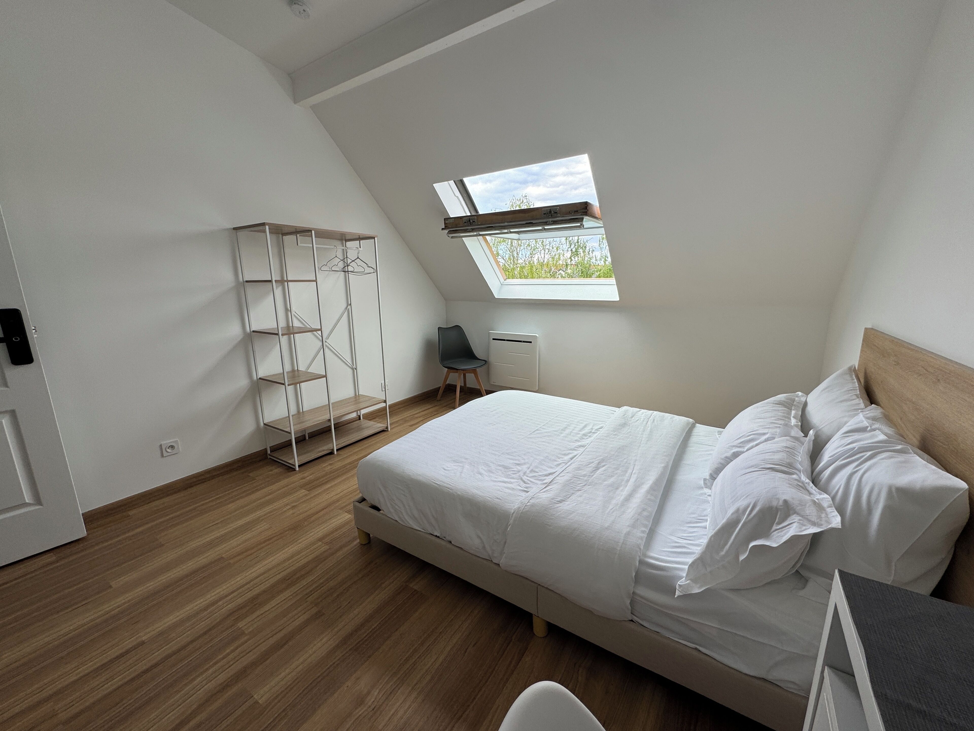 Une chambre à coucher avec un lit, une armoire, une chaise et une lucarne.