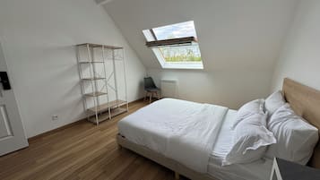 A bedroom with a bed, a wardrobe, a chair, and a skylight.