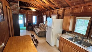 A rustic wooden interior with a dining table, kitchen area, and a cozy seating area. - Rustic View Cabin sits on a 2.5 acres on beautiful Hubbard Lake.   (Hubbard Lake)