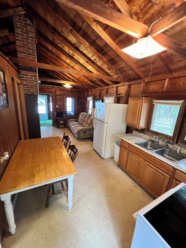 A rustic wooden interior with a dining table, kitchen area, and a cozy seating area.