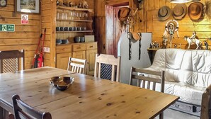 Un interior de madera con una mesa de comedor, sillas, un sofá y estanterías con cerámica.