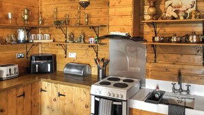 Cocina de cabaña de madera con estufa, tostadora y varios utensilios de cocina.