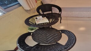 A room with a round wicker table and chairs, a white sofa, and a window with curtains. - OYO 75487 Prang Thip 306 Resort (Bangkok)