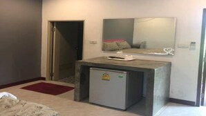 A compact hotel room with a bed, a small kitchenette, a refrigerator, a mirror, and an air conditioning unit. - OYO 75487 Prang Thip 306 Resort (Bangkok)