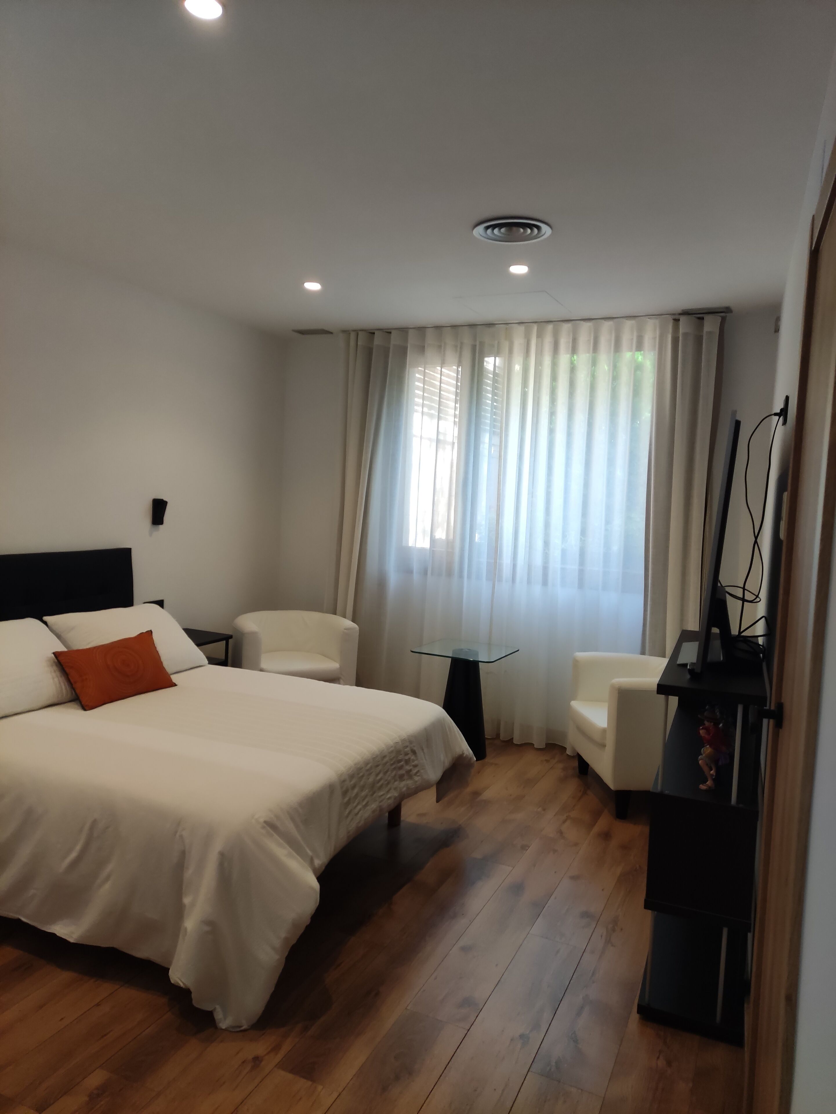 Une chambre d’hôtel avec un grand lit, deux chaises, une petite table et un meuble pour la télévision.