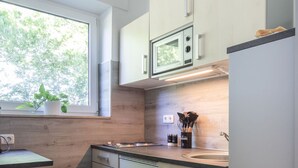 Una cocina moderna con armarios de madera clara, microondas integrado y ventana con vistas a zonas verdes.