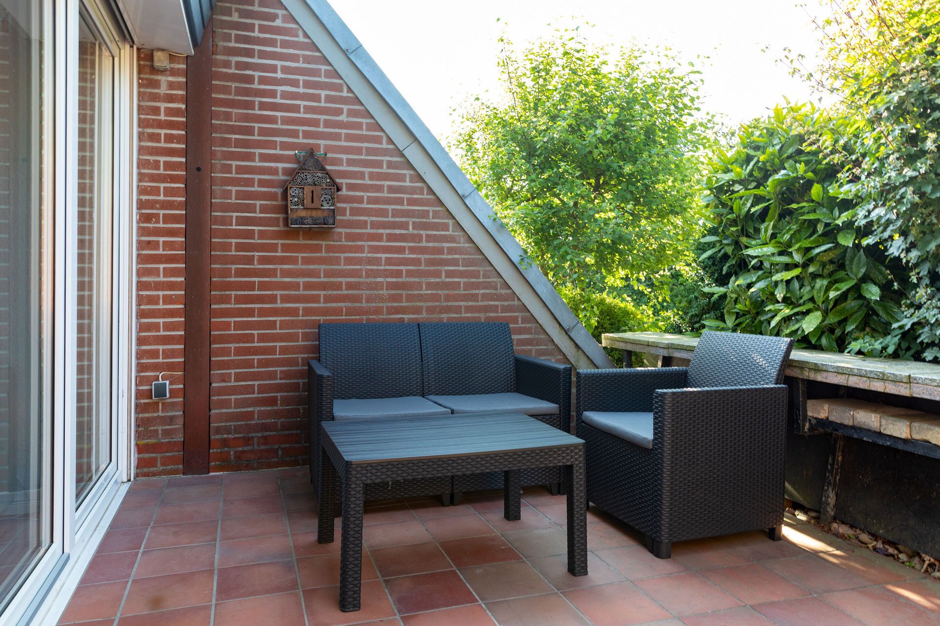A patio with wicker furniture, a brick wall, and a window.
