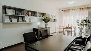 Een moderne eetruimte met een lange tafel, stoelen en een decoratieve vaas.