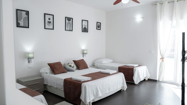 Een moderne hotelkamer met een groot bed, twee nachtkastjes, een plafondventilator en lijstwerken aan de muur.