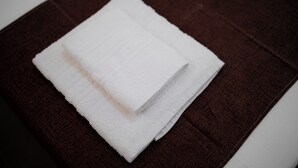Een witte handdoek gevouwen op een donkerbruine, getextureerde ondergrond.