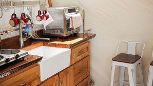 Een kleine keuken met houten kastjes, een wit aanrecht, een oven en een raam boven de gootsteen.