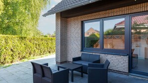 Eine Terrasse mit Korbmöbeln, einer Glastür und einer Ziegelwand.