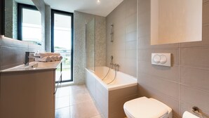Une salle de bain moderne équipée d’une baignoire, de toilettes et d’un lavabo.