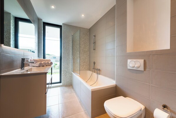 Une salle de bain moderne équipée d’une baignoire, de toilettes et d’un lavabo.